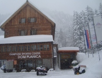 Leta 2005 so podrli propadajoči leseni Dom Ilirija iz leta 1931 in zgradili nov dom, zraven še hotel s telovadnico in obnovili depandanso. Zakaj se imenuje Olimpijski športni center, Dom Planica vedo le na Olimpijskem komiteju Slovenije, saj v Sloveniji, kaj šele v Ratečah ni bilo olimpijskih iger. Taka je navada v tujini, kjer so priredili to največjo športno prireditev.